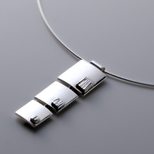 Graduated squares with smaller textured squares worn on a silver wire