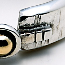 Textured band with gold ball set on a raised section of square wire 